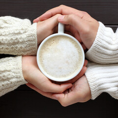 warming cappuccino in hands couple a top view. warming coffee atmosphere
