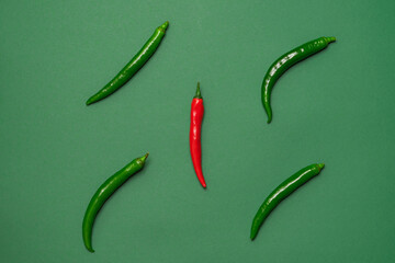 Four green and one red chili peppers on a green background. Minimalism photo