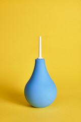 Medical rubber enema on yellow background with copy space. Shot with light shadow.