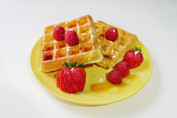 Waffles with syrup and red berries on plate and white background isolated 