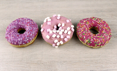 Three assorted pink round glazed donuts
