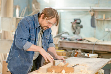 Hand of a carpenter taking measurement of a wooden plank