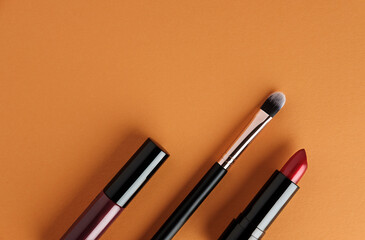 Set of makeup cosmetics on orange background.
