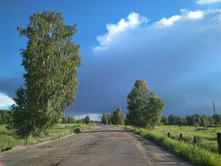 Fototapeta na wymiar dirt road travel for cars in summer with trees stormy sky with clouds