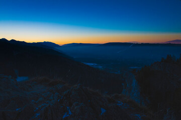 Bright sunset and clear sky over Podhale region, Poland. Rocky formations on the bottom of the picture can be found on the trail to Nosal Peak, Tatras. Selective focus on the ridge, blurred background