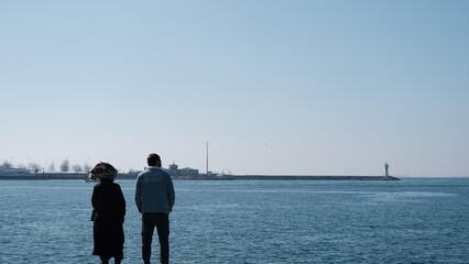 Turkey. Istanbul 04.03.2021.Istanbul bosphorus,sunny day. One man and girls standing on concrete port in Kadikoy shore and look at the marmara sea and transportation ferry in kadikoy. 