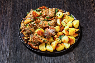 braised Rabbit with potatoes on a black plate