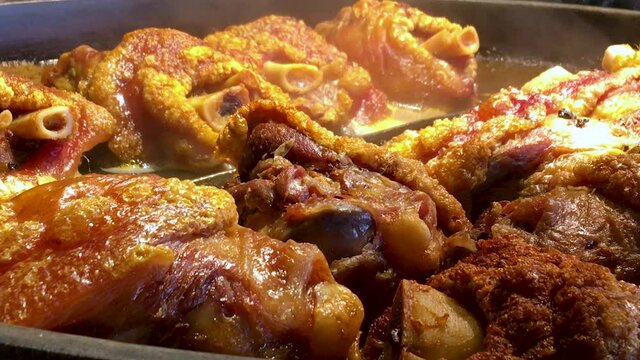 Pork shanks are stewed and baked in a huge frying pan. Hearty meat dish. 