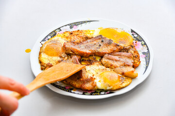 A woman lays fried eggs with meat on a plate.