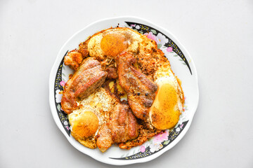 Fried meat and fried eggs on a plate, top view.