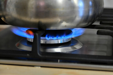 Kettle heats water on a gas stove, burning domestic gas close-up.