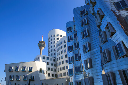 Dusseldorf (Medienhafen), Germany - March 1. 2021: View on Gehry houses with silver shiny futuristic metallic aluminium facade with tv tower