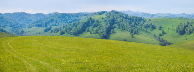 Obraz na płótnie Canvas Picturesque valley, panoramic mountain view. Bright sunlight, spring greens of forests and meadows.