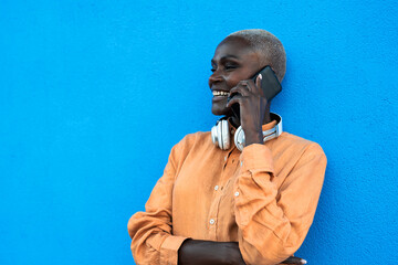 African woman doing a call with mobile smartphone while standing on blue background