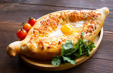 Georgian national dish adjarian khachapuri on a wooden background. National Georgian pastries with cheese and raw eggs