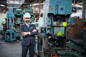 Portrait of confident business people wearing hardhats in metal factory