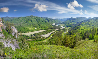 Tourism in Altay, Russia. View of the valley and the Katun River from the mountain. Spring panoramic view. Green forests and meadows and a beautiful sky.