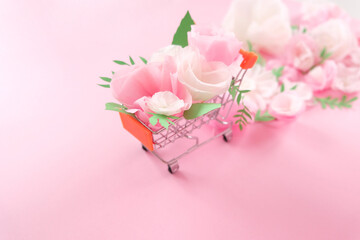 Hello, spring. Shopping cart with white and pink paper flowers and green leaves