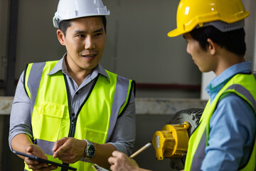 Senior and junior engineers talking together with intimated manner beside the machine in factory....