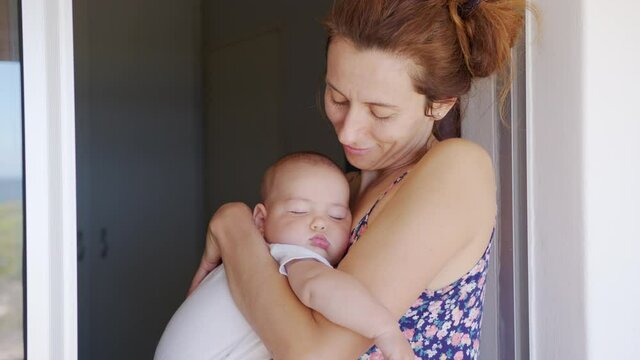 Close up of mother hugging and kissing sleeping baby daughter holding her in my arms.