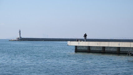 Turkey. Istanbul 04.03.2021.istanbul kadikoy, people fishing and walking on concrete shore bosporus istanbul near haydarpasa main train station during sunny day. 