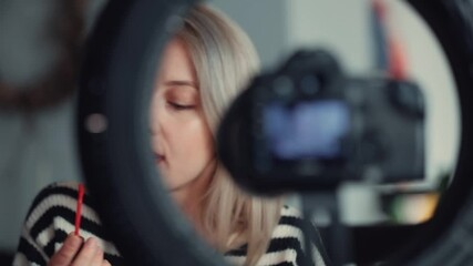 Blonde blogger recording a vlog about cosmetics at home during a pandemic