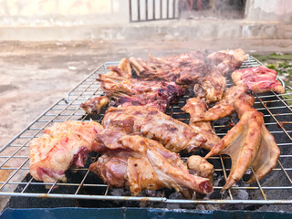 Duck meat that has been split into pieces Then being marinated with sauce And are roasting on the stove with charcoal.