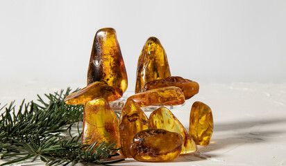 Lots of sparkling transparent yellow-orange amber stones on a white background.  Amber texture, material for jewelers, stone healing, amulet. 