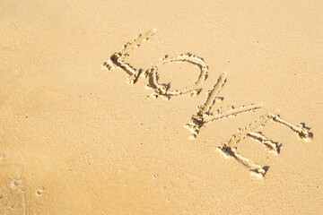 Love lettering on the sand of the beach. Travel, love. Top view.