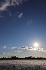 Dutch farmland covered by white snow with in the distance a small church.