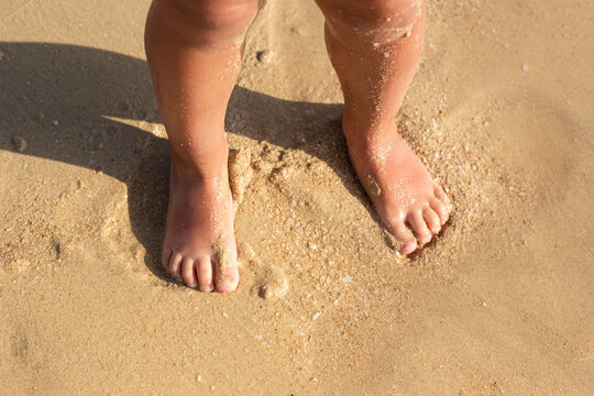 two feet, child feet on the sand at the beach.