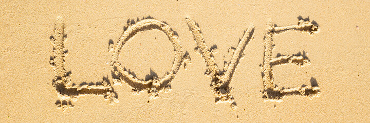 lettering Love on the sand of the beach on a sunny day. Top view. Banner.
