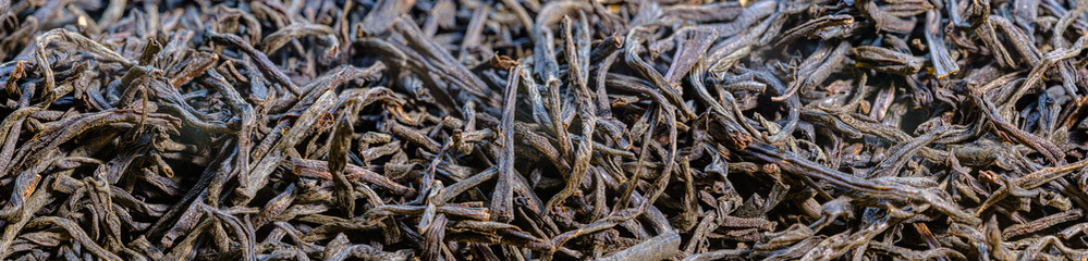 Scattered black tea close-up. panoramic view of dry tea leaves. Macro shot of tea brewing.