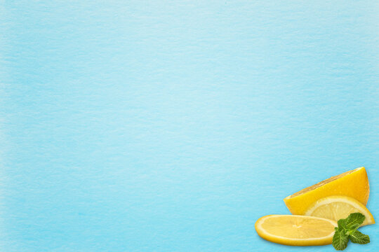 A Leaf Of Blue Watercolor Paper And In The Corner Of A Two Lemon Wedge And A Half Of A Lemon And A Top Green Mint