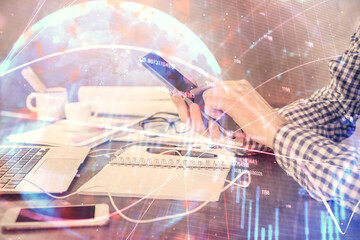 Double exposure of man's hands holding and using a digital device and forex graph drawing. Financial market concept.