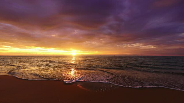 Tropical beach and ocean at sunrise. Ocean waves splashing on the sand.