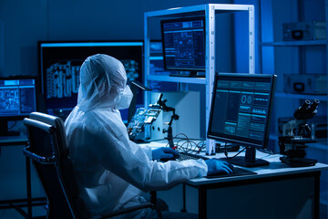 Microelectronics engineer works in a modern scientific laboratory on computing systems and microprocessors. Electronic factory worker is testing the motherboard and coding the firmware.