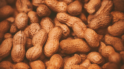 Top view of a large number of ripe peanuts in shells lying in a grocery store, illuminated by light. A rich crop of nuts.