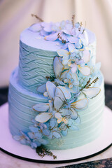 blue wedding cake with mastic butterflies on the table. Picture for a menu or a catalog of confectionery products.