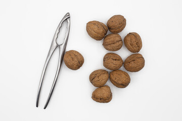 Walnuts and nutcracker isolated on white background with shadows. Top view, horizontal shot