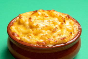 Mac and cheese bowl close-up, isolated on a green background.