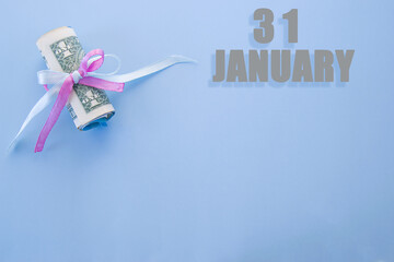 calendar date on blue background with rolled up dollar bills pinned by blue and pink ribbon with copy space. January 31 is the thirty-first day of the month