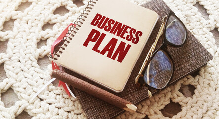 Words Business plan on copybook cover, glasses, pen and book Business brief review and conclusions...