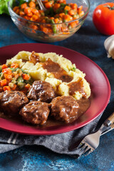 Roasted meatballs in dark sauce with mashed potatoes