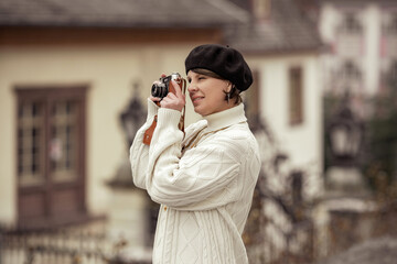 Fototapeta premium woman photographer in birette with an old camera in her hands takes pictures with smile
