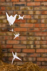 White paper cranes Japanese against the background of a brick wall