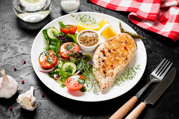 Grilled chicken breast with fresh vegetable salad. Healthy food, keto diet, diet lunch concept. On black stone background