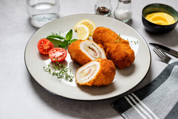 French traditional cuisine crispy, creamy chicken cordon bleu on gray background.
