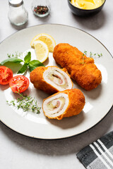 French traditional cuisine crispy, creamy chicken cordon bleu on gray background.