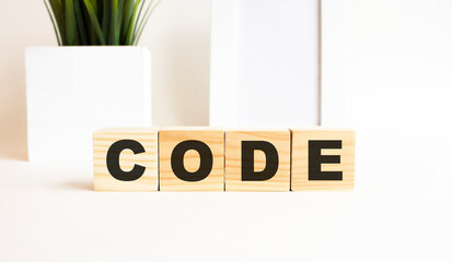 Wooden cubes with letters on a white table. The word is CODE. White background.